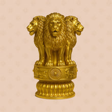Gold statue of three lions on a decorative pedestal against a beige background